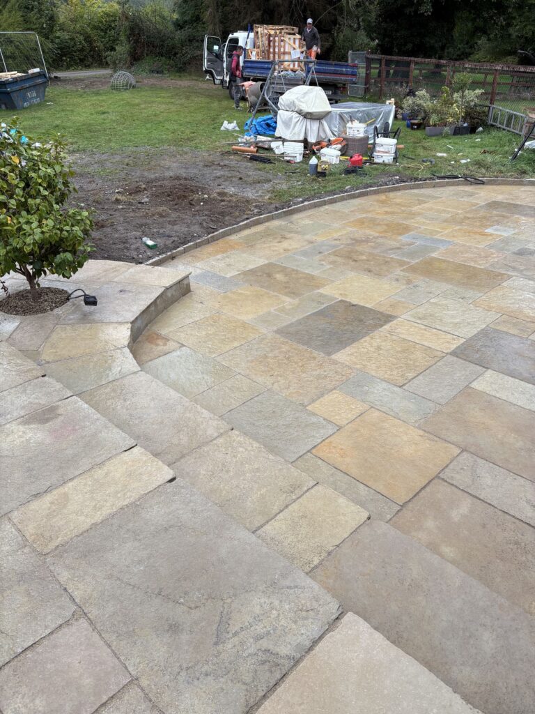Newly laid sandstone patio with steps, surrounded by construction materials and a grassy area in Wicklow