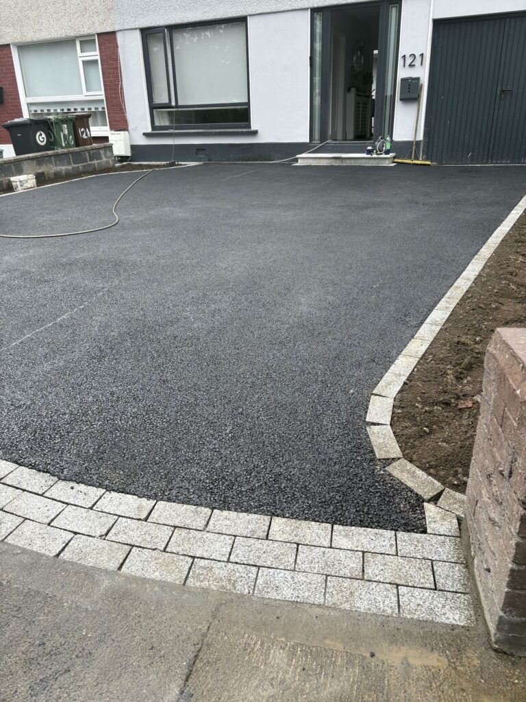 Newly paved driveway with dark asphalt, bordered by light stone edging, in front of a residential building in Wicklow