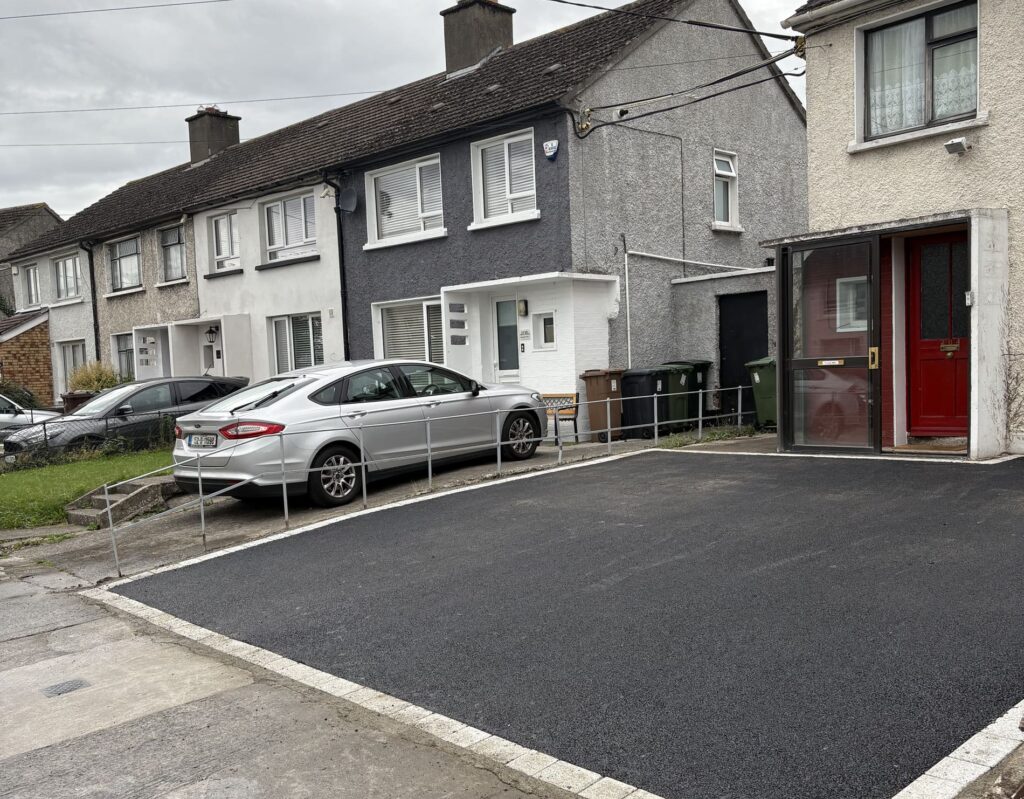 Silver car parked on a newly paved driveway in front of residential houses in Wicklow, with green bins nearby