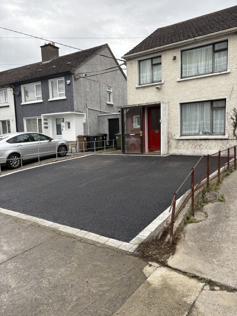 Newly paved black driveway with white edging, adjacent to two residential houses in Wicklow, with a silver car parked nearby