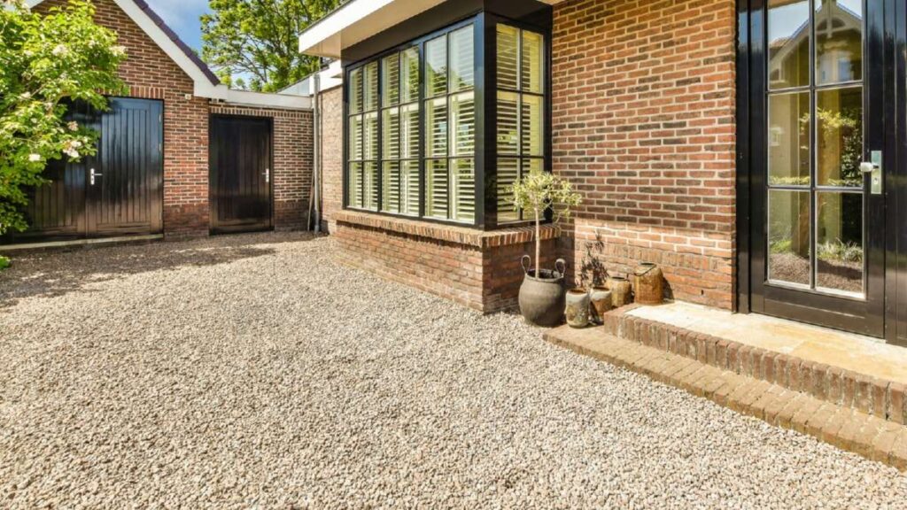 Gravel driveway leads to a modern brick home with large windows, potted plants, and two dark wooden doors in Wicklow