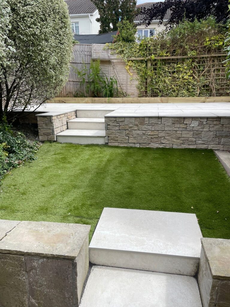 Modern patio with stone steps, artificial grass, and greenery, showcasing stylish landscaping in Wicklow