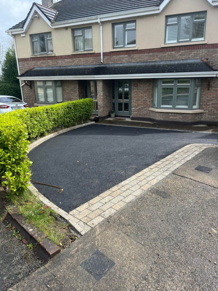 Driveway with black asphalt and stone edging, surrounded by green hedges, in front of a residential home in Wicklow