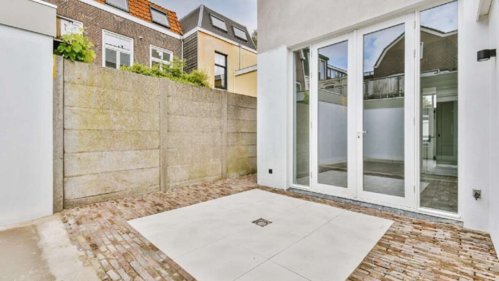 Bright outdoor space with a paved area, large glass doors, and a concrete wall, showcasing potential for Driveways Wicklow