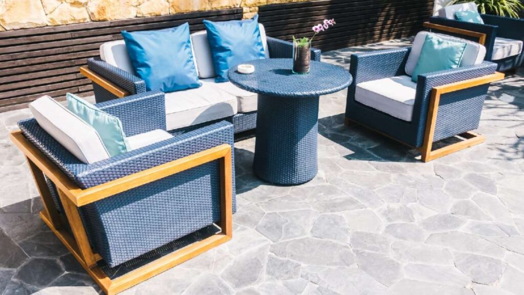 Outdoor seating area with navy wicker chairs and table, accented by light blue cushions on a stone patio. Driveways Wicklow