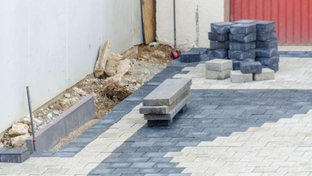 Paved driveway under construction with stacked blocks, gray and beige patterns, near a red wall in Wicklow
