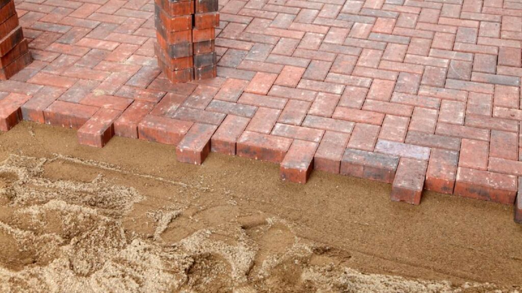 Red and gray brick pavers form a driveway edge, with sand visible beside the unfinished area in Wicklow