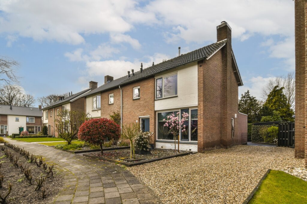 Residential building with gravel driveway, landscaped garden, and flowering trees under a partly cloudy sky in Wicklow