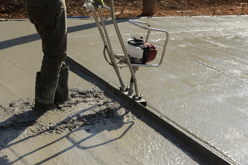 Worker in rubber boots using a concrete screed on a freshly poured surface for concrete driveways South Dublin