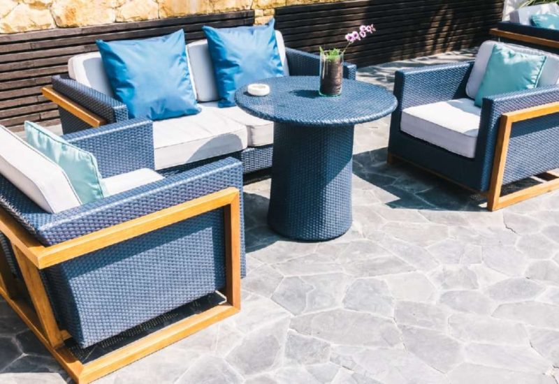 Outdoor seating area with navy wicker chairs and table, accented by light blue cushions on a stone patio. Driveways Wicklow